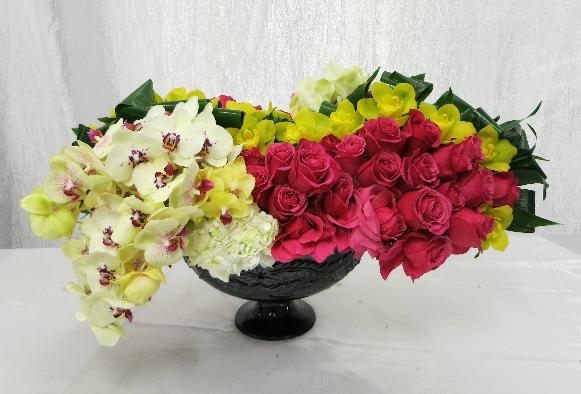 Orchid Opulence  - An eye-popping display of rich colors made with roses and both cymbidium and phalaenopsis orchids in an arrangement full of movement.  *vase subject to availability