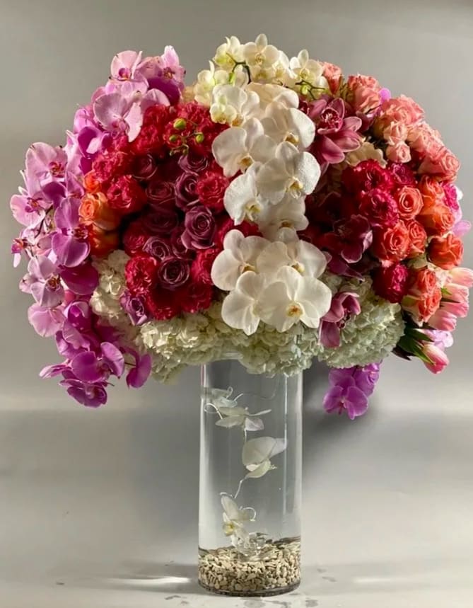 Fairytale - A grandiose and opulent display of coral, purple, and pink blooms of the highest standards. This stunning display of roses, tulips, and cymbidium orchids is draped lovingly with the ever luxurious phalaenopsis orchids. A truly exquisite arrangement that's sure to impress!  *PLEASE allow at least 24 hours advance notice to guarantee the most quality blooms*