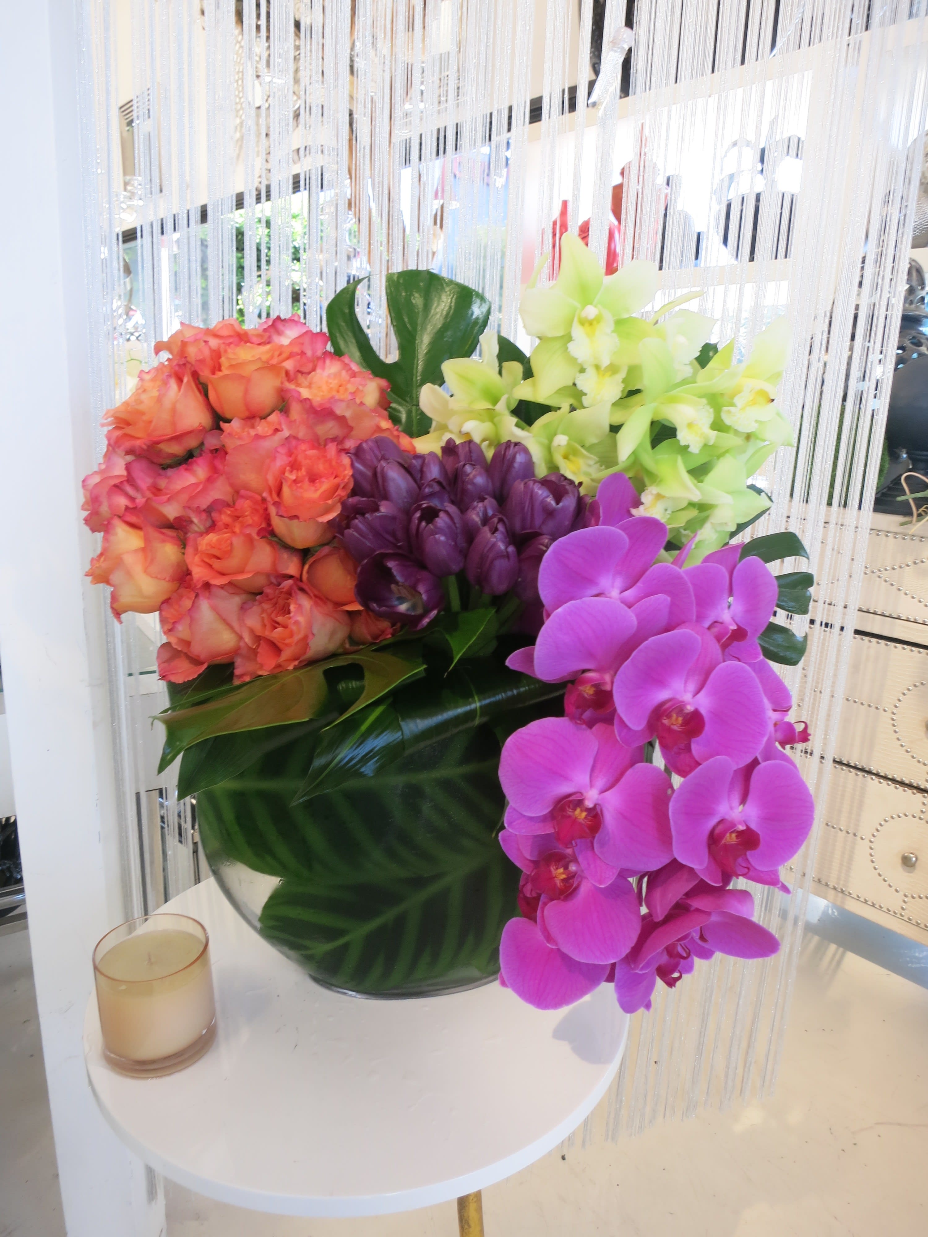Her Majesty  - Fuschia phalaenopsis orchids, purple tulips, and coral  roses in a zebra leaf-lined vase.