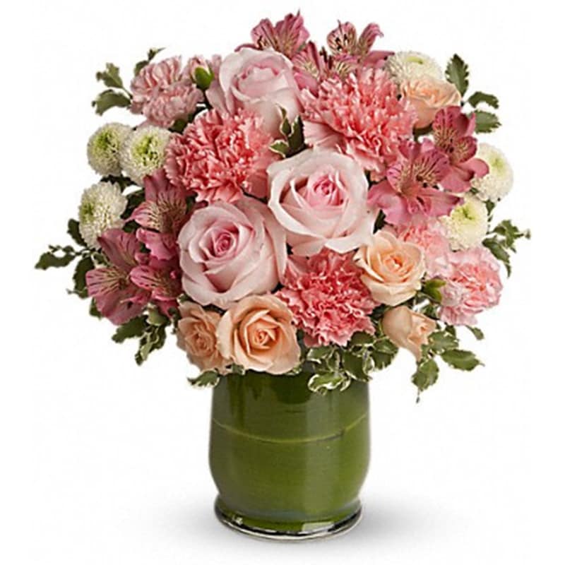 Roses &amp; Smiles - A guaranteed smile-getter, this fabulously feminine bouquet includes radiant roses, delicate alstromeria and cheerful carnations in soft shades of pink and peach. Presented in a simple leaf-lined vase, it's a great way to pink up anyone's day!  Roses of pale pink and peach are mixed with pink carnations, pink alstroemeria and white mums. Variegated pittosporum adds a touch of green. Presented in a clear glass vase lined with a deep green ti leaf.  Product ID: T596-1A