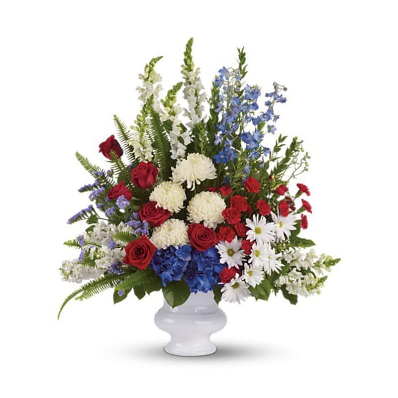 With Distinction With Distinction - A dazzling display of patriotic red, white and blue flowers sends a silent yet poignant statement about hope, freedom and the strength to endure. This proud bouquet is a testament to life that is sure to be appreciated. A beautiful mix of all-American red, white and blue flowers such as hydrangea, roses, miniature carnations, snapdragons, chrysanthemums and more are perfectly arranged in a white urn.