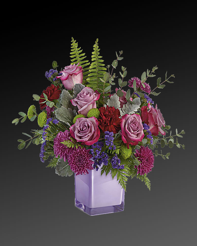 Purple Serenity Bouquet - A serene style statement in lush lavender roses and fresh maroon blooms, this rich bouquet in an amethyst-colored cube is a beautiful surprise for any occasion! Lavender roses, maroon carnations, purple cushion spray chrysanthemums, green button spray chrysanthemums, and purple sinuata statice are accented with sword fern, leatherleaf fern, dusty miller, and parvifolia eucalyptus.