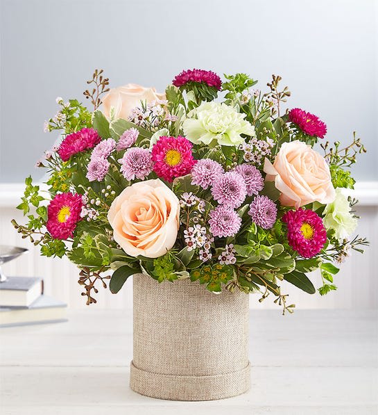 Glorious Day™ Bouquet - Every glorious day begins with fresh, beautiful flowers…and our new bouquet has a lot! Soft peaches and lavenders mix with hot pink and lime green, all gathered in our neutral-toned hatbox to really let each bloom shine.