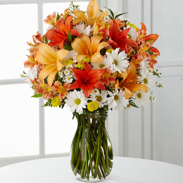 Sunrise Sentiment  - Picked fresh from the farm to bring energy and vibrant blooming beauty to your special recipient's day, the Sunrise Sentiments Mixed Flower Bouquet is set to lift spirits and celebrate life's most treasured moments. Hand gathered in select floral farms and boasting a sunlit beauty showcased in orange, yellow and white hues, this eye-catching flower arrangement has been picked fresh for you to send your warmest happy birthday, get well, or congratulations wishes to friends and family near and far. This bouquet includes the following: orange Asiatic Lilies, white monte casino asters, yellow button poms, and an assortment of  Presented with a clear rectangular glass vase. BETTER bouquet is approximately 14&quot;H x 13&quot;W. 