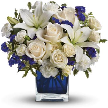 Sapphire Skies Bouquet -     Like gazing into a clear blue sky, this serene arrangement soothes the soul and cheers the heart. Its creamy roses and snowy lilies are arranged in our dazzling sapphire cube.  Crme roses, white asiatic lilies and white miniature carnations are mixed with bursts of purple statice and green pitta negra. 