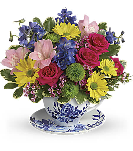 Teleflora's Dutch Garden Bouquet Teleflora's Dutch Garden Bouquet - Pour on the charm! Brighten any occasion with this cheerful bouquet of pink roses, blue delphinium and yellow daisies, beautifully bunched in a classic, Delft-inspired teacup and saucer set!