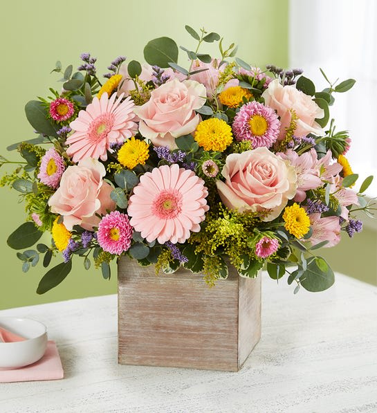 Spring Sentiment Bouquet - Spring is a time to refresh and reach out. Our new spring bouquet celebrates that sentiment. Soft pink and yellow blooms are loosely gathered with lush greenery for style and texture. Designed in our rustic, grey-washed wooden cube, it’s a gift that delivers on your feelings in the most beautiful way.  All-around arrangement with pink roses, mini Gerbera daisies, Matsumoto asters and Peruvian lilies (alstroemeria); yellow button poms and purple limonium; accented with assorted greenery Artistically designed in our rustic, natural wood-grain cube container; measures 5&quot;W x 5&quot;L arrangement measures approximately 12&quot;H x 12&quot;W Our florists hand-design each arrangement, so colors and varieties may vary due to local availability To ensure lasting beauty, Peruvian lilies arrive in bud form, ready to bloom in a few days 