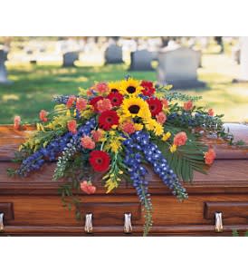 Vibrant Summer Casket Spray [TF202-1] - Pay tribute to a colorful, rich life with this casket spray of summer flowers.  One casket spray arrives decorated with radiating stalks of hybrid blue delphinium and clusters of red gerberas, yellow sunflowers and orange carnations.  Approximately 47&quot; W x 32&quot; H      As Shown : TF202-1  