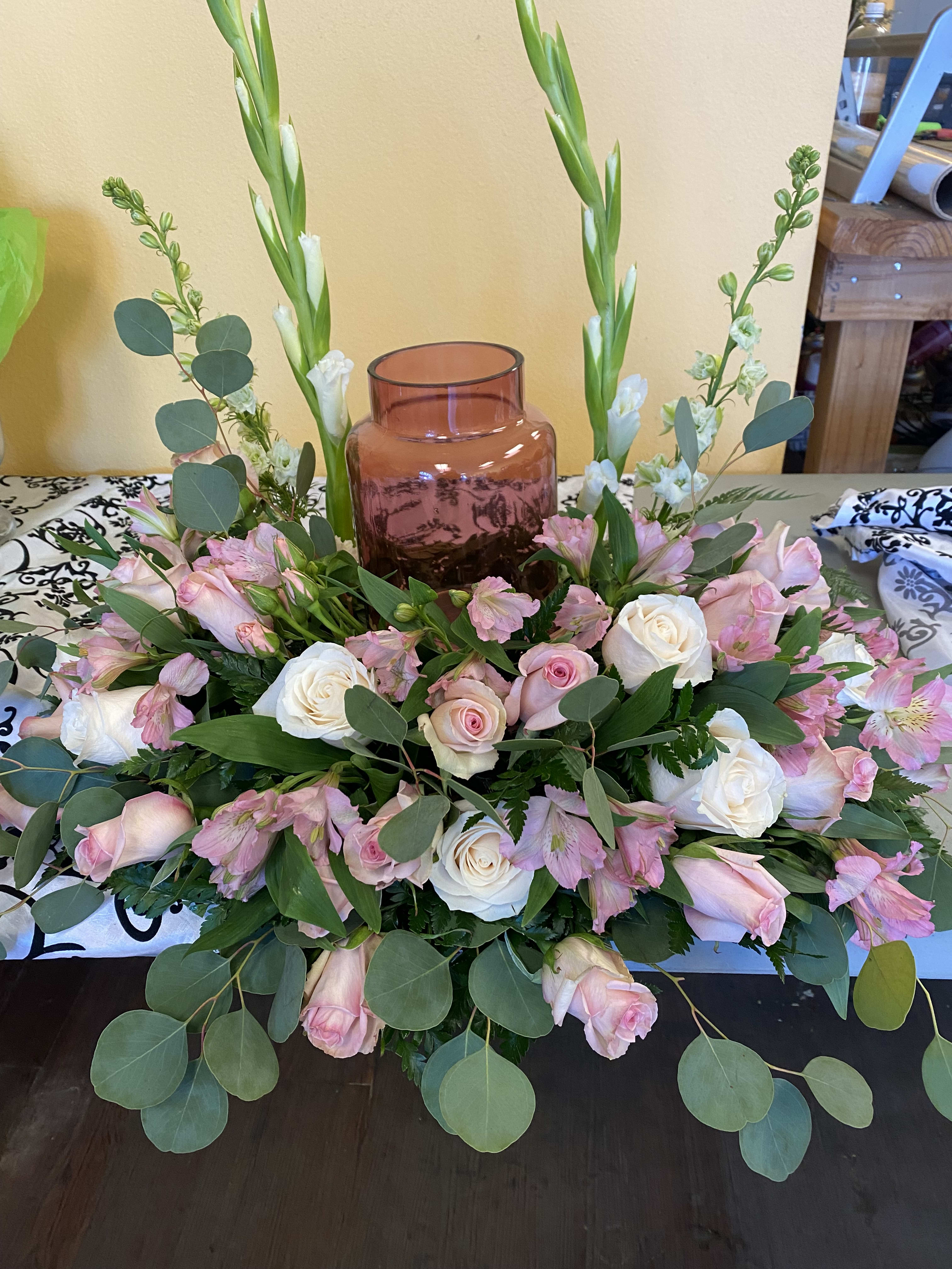 URN (CENTERPIECE) PINK AND WHITE URN (CENTERPIECE) PINK AND WHITE - DESINGER CHOICE URN CENTERPIECE WITH WHITE AND PINK FLOWERS. VASE IS NOT INCLUDED IT IS JUST TO SHOW HOW IT WOULD LOOK ONCE THE URN IS PLACED INSIDE THE CENTERPIECE. FLOWERS TO INCLUDE ROSES, GLADIOLAS, LARKSPUR AND SILVER DOLLAR EUCALIPTUS. THIS CENTEPIECE ONLY HAS FLOWERS ON THE SIDES AND THE FRONT NO FLOWERS IN THE BACK, JUST GREENARY.