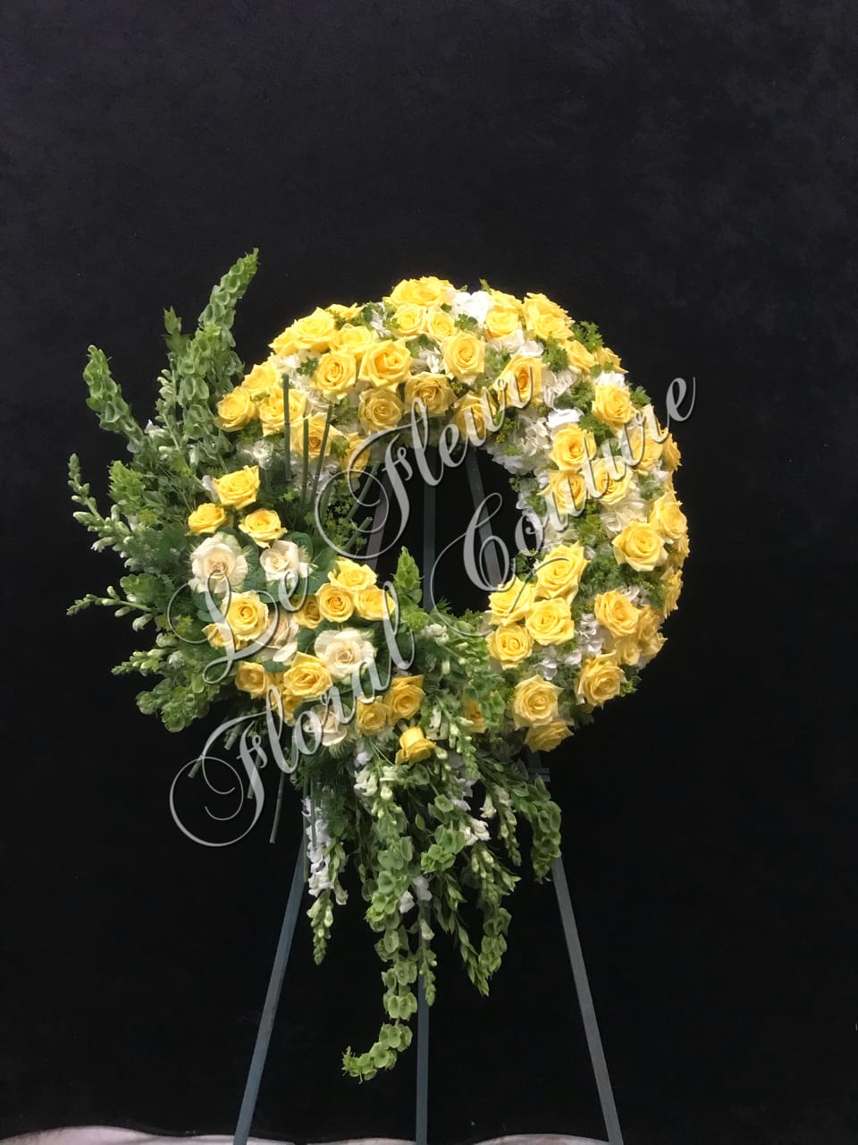 Winding Meadow Sympathy Wreath - A unique sympathy wreath, with a winding floral cluster. Consisting of roses, hydrangeas, bell of Ireland,snap dragons, solidago and kale flower.  