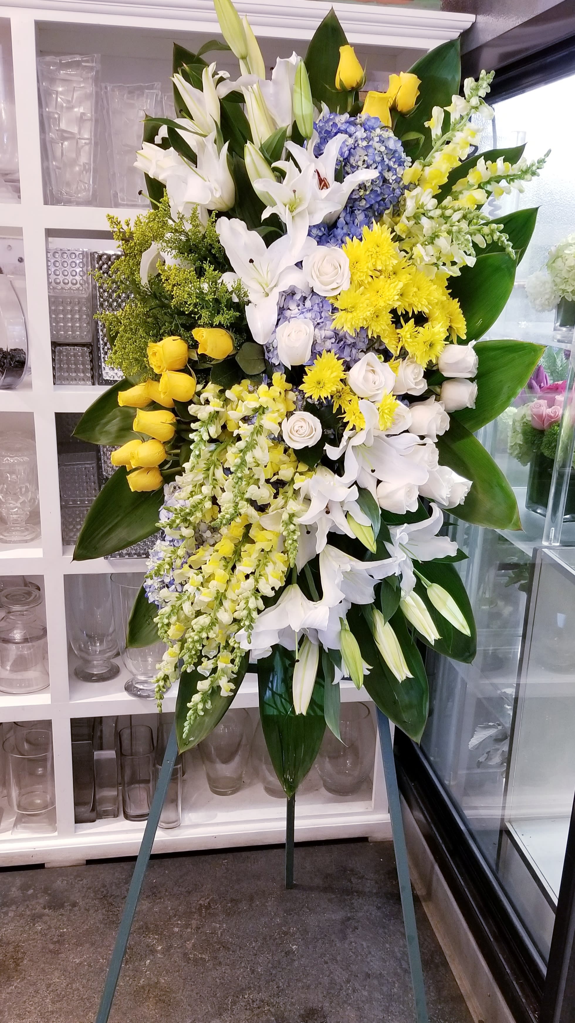 Memories - Funeral standing spray in white, yellow and a touch of blue.
