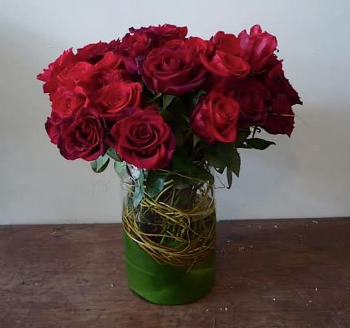 Beauty Beauty - Rich red roses with curly willow branches in a glass vase.