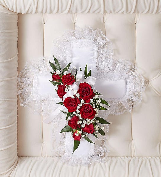 Red &amp; White Satin Cross Casket Pillow - A tasteful memento of faith and love for the dearly departed to take with them. Our satin cross casket pillow, fashioned by our expert florists with a spray of radiant red spray roses and white ribbon, is a simple yet elegant arrangement and a touching ornamental gesture.  Cross-shaped satin casket pillow is adorned with a spray of red roses, baby’s breath, ribbon and soft, lush greenery Measures approximately 9”L x 9”W Appropriate for the funeral home Our florists use only the freshest flowers available, so colors and varieties may vary