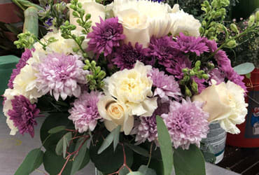 LAVANDER BOUQUET LAVANDER BOUQUET - "These luxurious lavender roses and crisp white lilies are poised to please! Perfectly presented in a stylish cube vase, it’s an any-occasion surprise they’ll never forget! Lavender roses, white Asiatic lilies, purple carnations, lavender carnations, purple button spray chrysanthemums and lavender button spray chrysanthemums are arranged with lavender Limonium and pitta Negra. Delivered in a glass cube. SET: One-Sided"