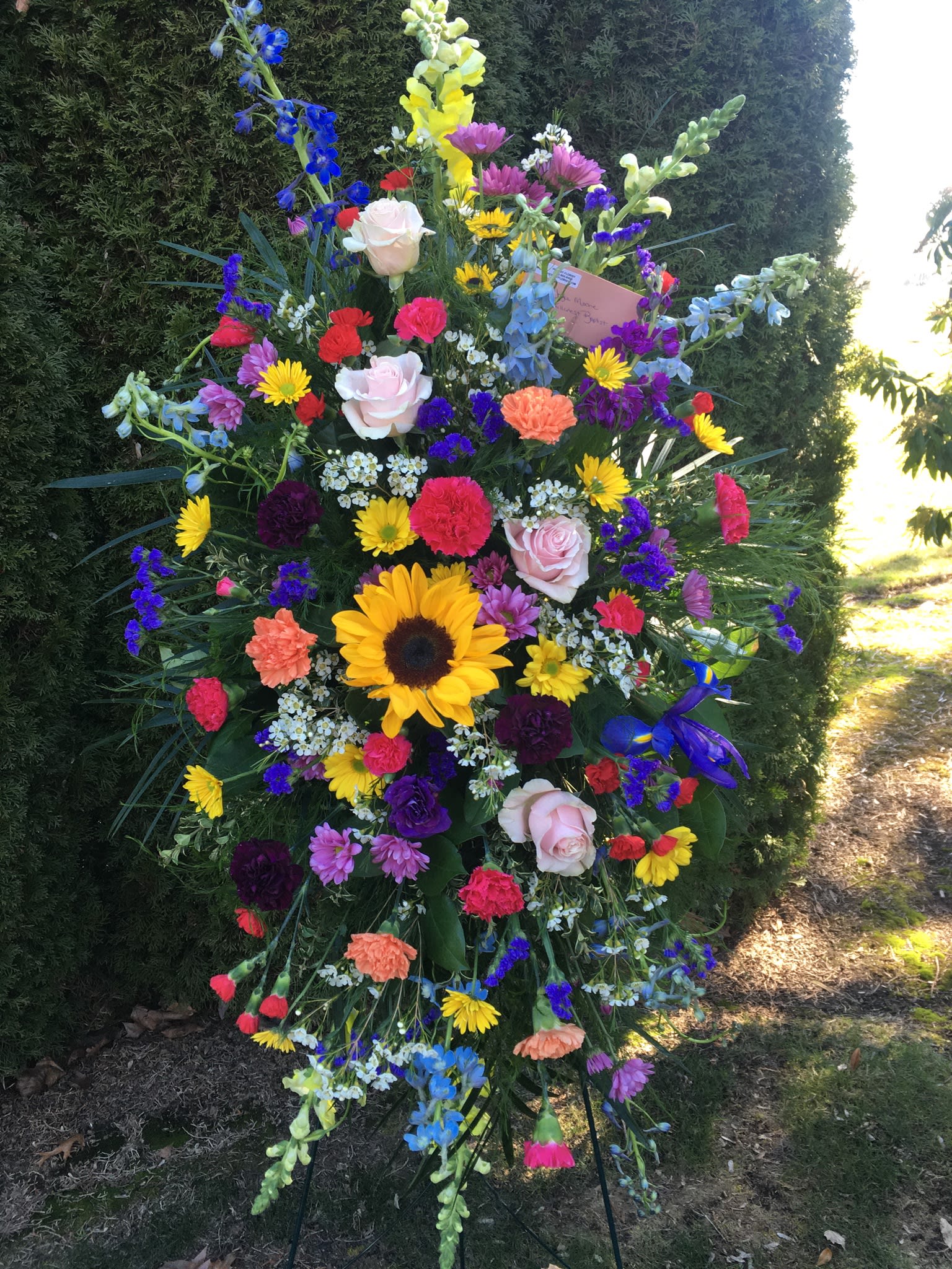 Garden easel spray  (3 Day Advanced Ordering Notice Required)  - This easel spray is made with a variety of colors and flowers to celebrate all the beauty of the outdoors for that special loved one. Sending your love and thoughts with this garden tribute.