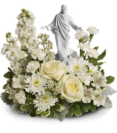 Forever Faithful Bouquet - An elegant display of faith and grace, this beautiful arrangement will comfort the bereaved in a truly thoughtful and respectful way. An exquisite sculpture of Jesus is surrounded by a bed of lovely blossoms. It is sure to be appreciated and always remembered.  A fragrant mix of pure white blooms - including roses, alstroemeria, stock, carnations and waxflower - is accented with dusty miller and variegated pittosporum. Delivered with an exclusive Sacred Grace keepsake. Approximately 18&quot; W x 13 1/2&quot; H