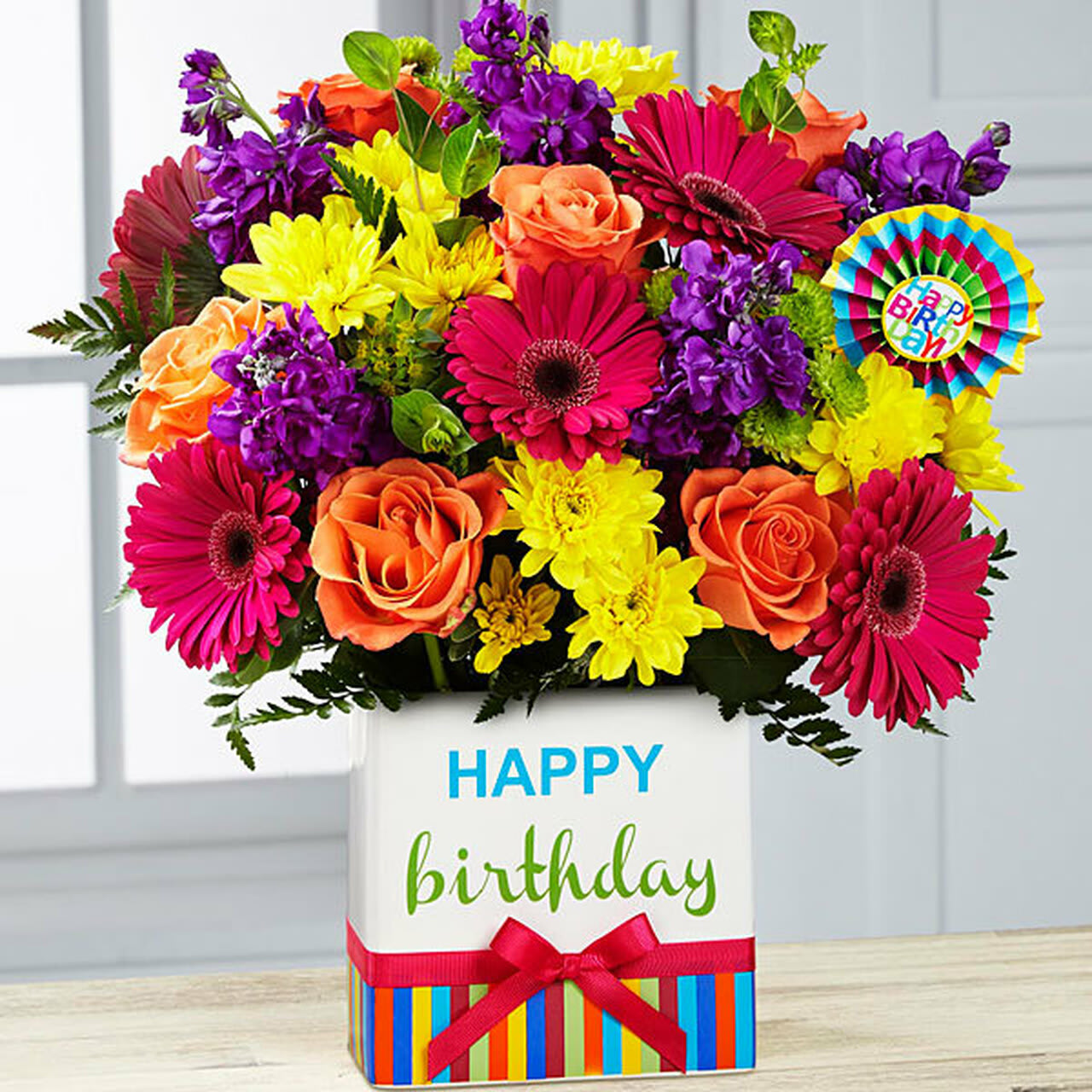 Birthday Brights Bouquet - Our popular Birthday Brights Bouquet is a true celebration of colour and life to surprise and delight your special recipient on their big day! Hot pink gerbera and orange roses along with purple stock, yellow mums, orange carnations, green button poms and more, create a party perfect birthday display. This festive flower arrangement is presented in an exclusive Happy Birthday ceramic vase with added Happy Birthday pic.