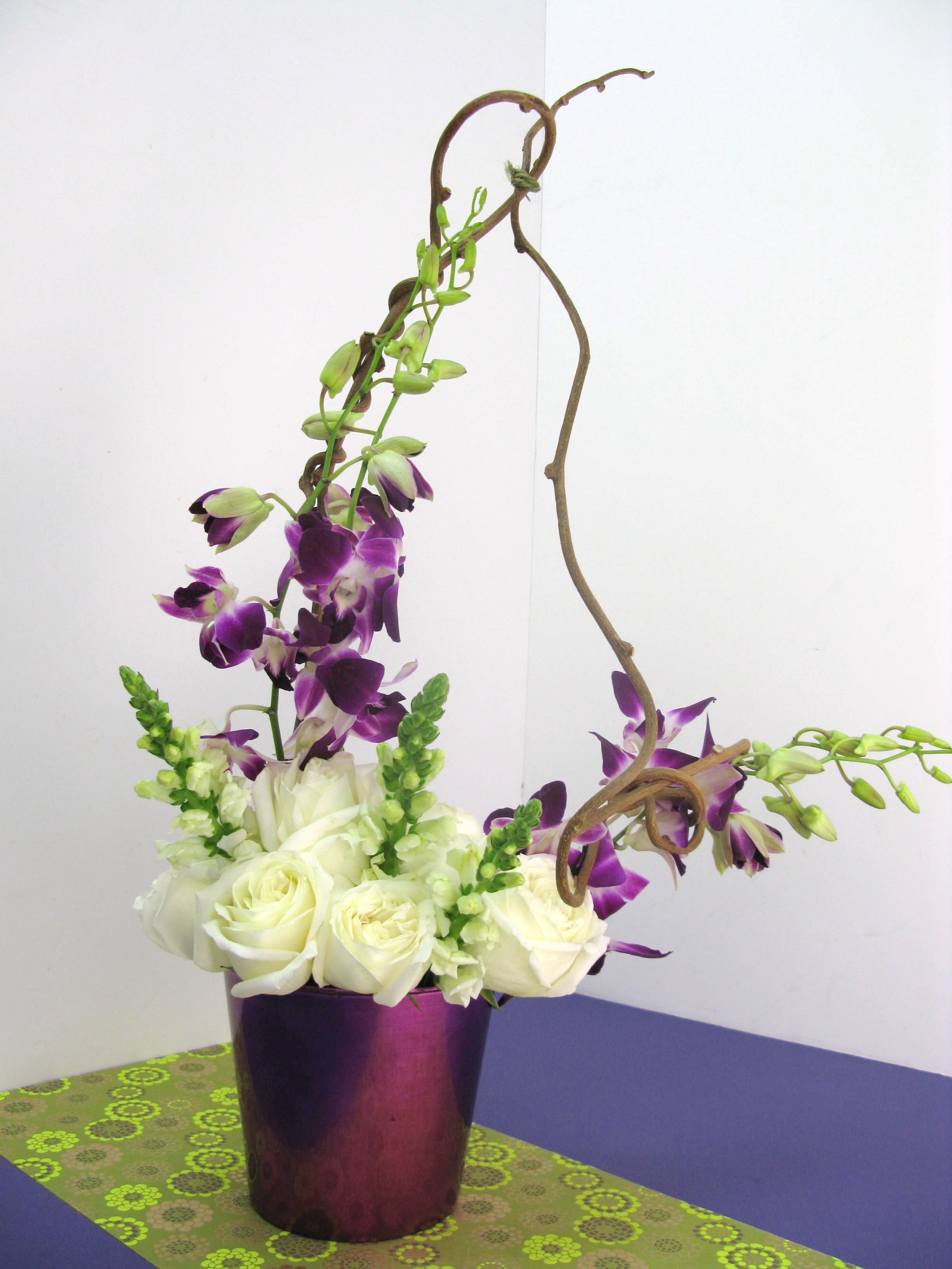 Extravaganza Purpura Extravaganza Purpura - This unique arrangement represents all that is pure and youthful. Designed to inspire feelings of peace and the promise of new beginnings, as it includes white roses and snapdragons with purple orchids.