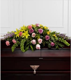 The Forever Belove Casket Spray - The  Forever Belove Casket Spray beautifully illuminates the atmosphere of thier final farewell service. Lavender roses, pink roses, lavender larkspur, pink carnations, Bells of Ireland, yellow Asiatic lilies, yellow freesia, solidago and lush greens are arranged to create an extravagant display of floral beauty that offers comfort and peace to the friends and family of the deceased. Approximately 43&quot;W x 30&quot;D. Your purchase includes a complimentary personalized gift message.