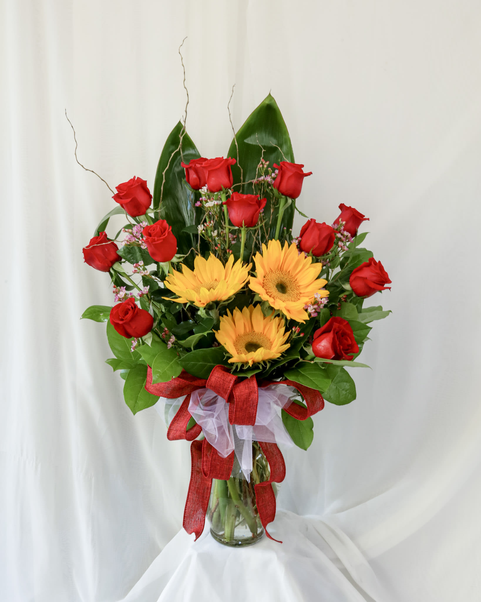 XOXO Flowers XOXO Flowers - This arrangement is a simple yet captivating piece. With a dozen roses and three sunflowers it is a wonderful gift to give to show how much you appreciate someone.