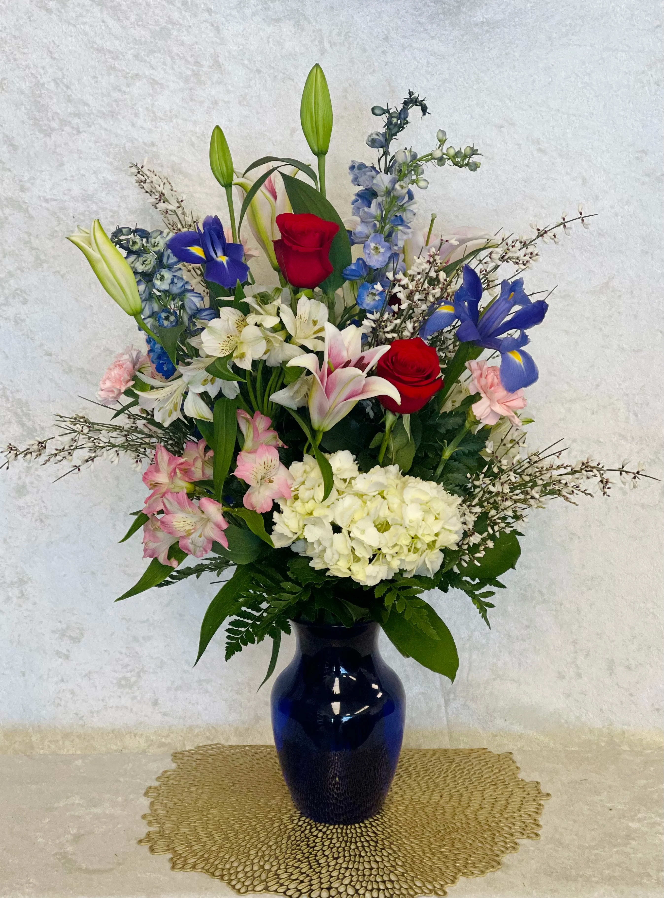 Blue Eyes! Blue Eyes! - A gorgeous bouquet for any occasion! If you're looking to put a smile on a special someone, this the perfect option. Includes: * White Hydrangea * Red Roses * Pink and White Alstroemerias * White Wax Flowers * Blue Delphinium * Blue Irises * Pink Lillys * Pink Carnations * Fresh Greens * Glass Vase * Orientation: All-Around * Delivery Available for today