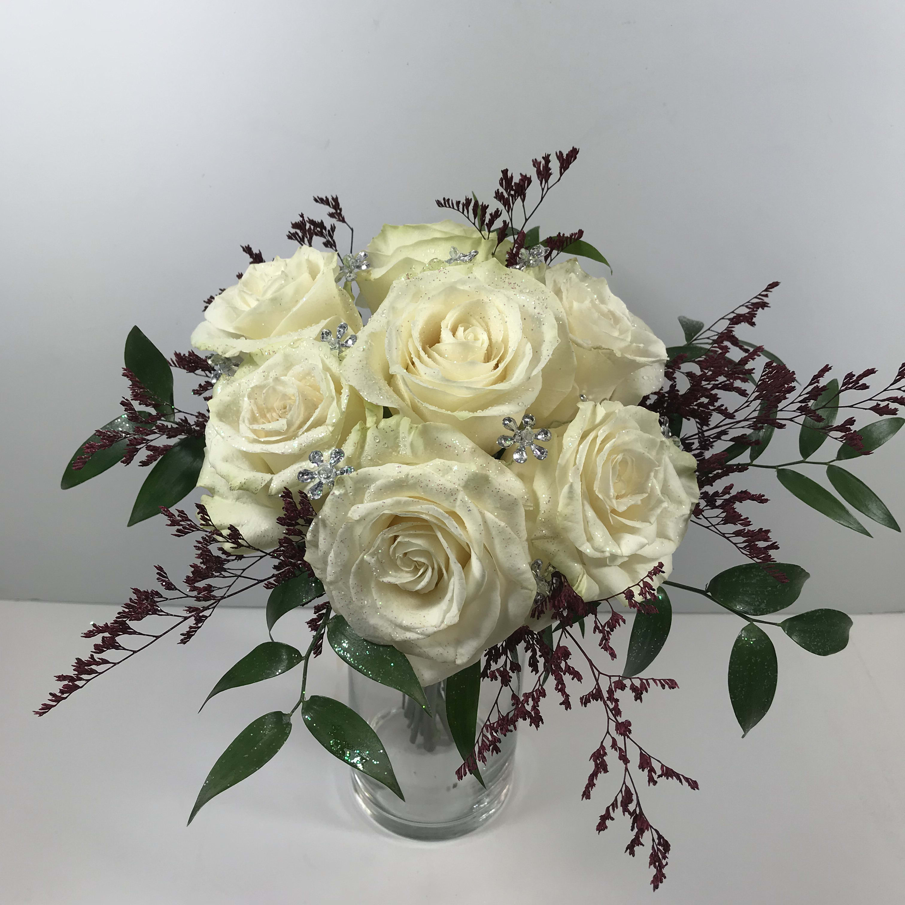 C69 Bejeweled White Rose Clutch with accent colored foliage C69 Bejeweled White Rose Clutch with accent colored foliage - White rose prom clutch with sparkling jewels and painted limonium to match her dress. Each order is customized for you and your date's amazing gown.
