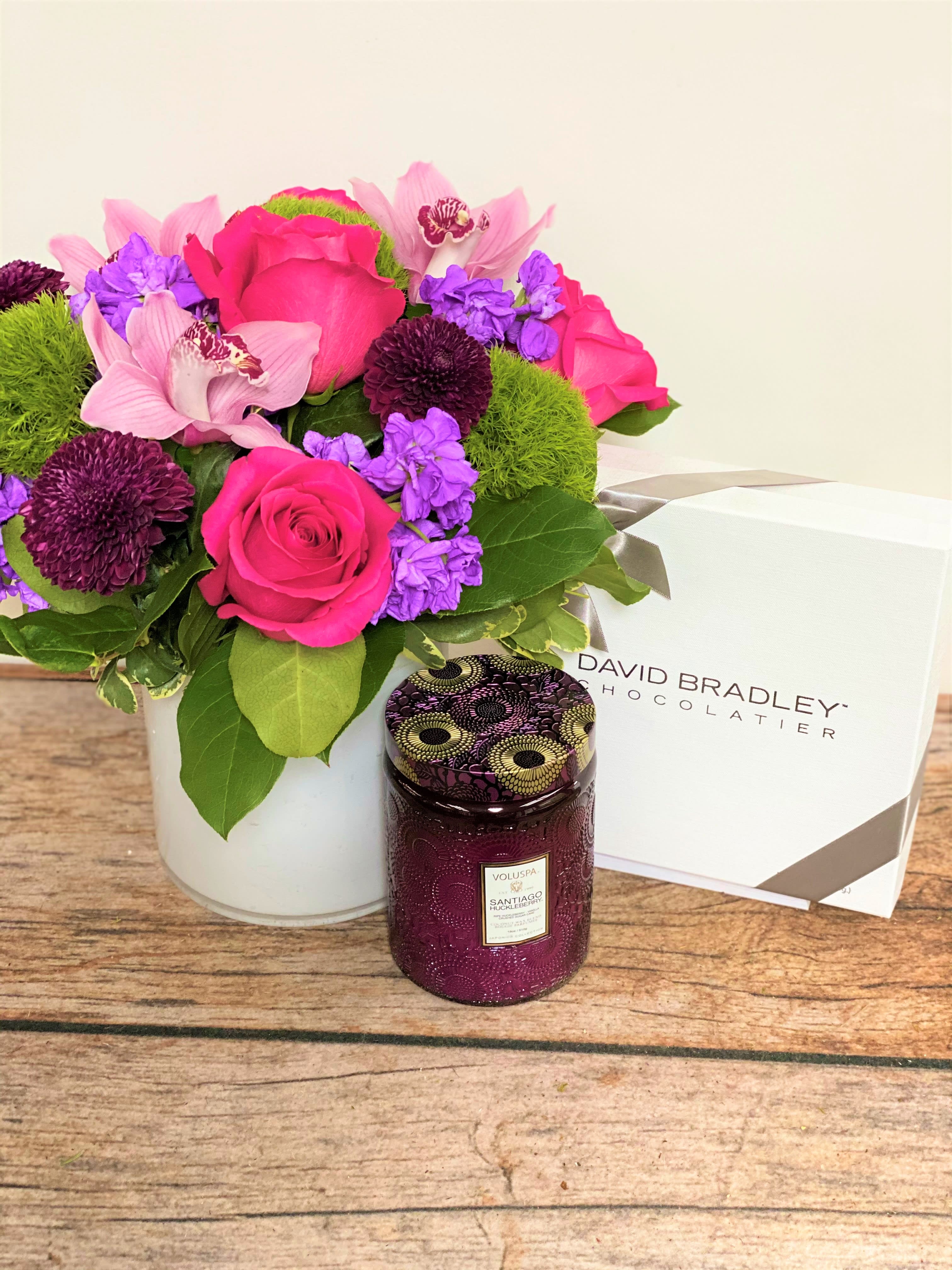 Complete Package - All packaged and ready to go! A full, mixed floral arrangement accompanied by a Voluspa candle and one pound box of mixed David Bradley Chocolates. Everything your Valentine needs and wants!