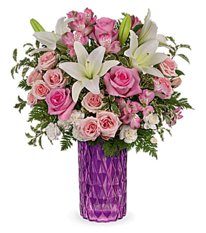 Teleflora's Rose Glam Bouquet - Standard - 20&quot;H x 18&quot; W Deluxe - 21 1/4&quot; H x 17 1/2&quot; W (additional roses) Premium - 21 1/4&quot; H x 18 1/2&quot; W (additional roses)  Bursting with perfect pink roses and snow white lilies, this sparkling cut glass vase in the most glamorous shade of amethyst is a Mother's Day gem. This bouquet features pink roses, pink spray roses, white asiatic lilies, miniature white carnations, pink alstroemeria, pitta negra and leatherleaf fern. Delivered in Teleflora's Amazing Amethyst vase. Orientation: All-Around