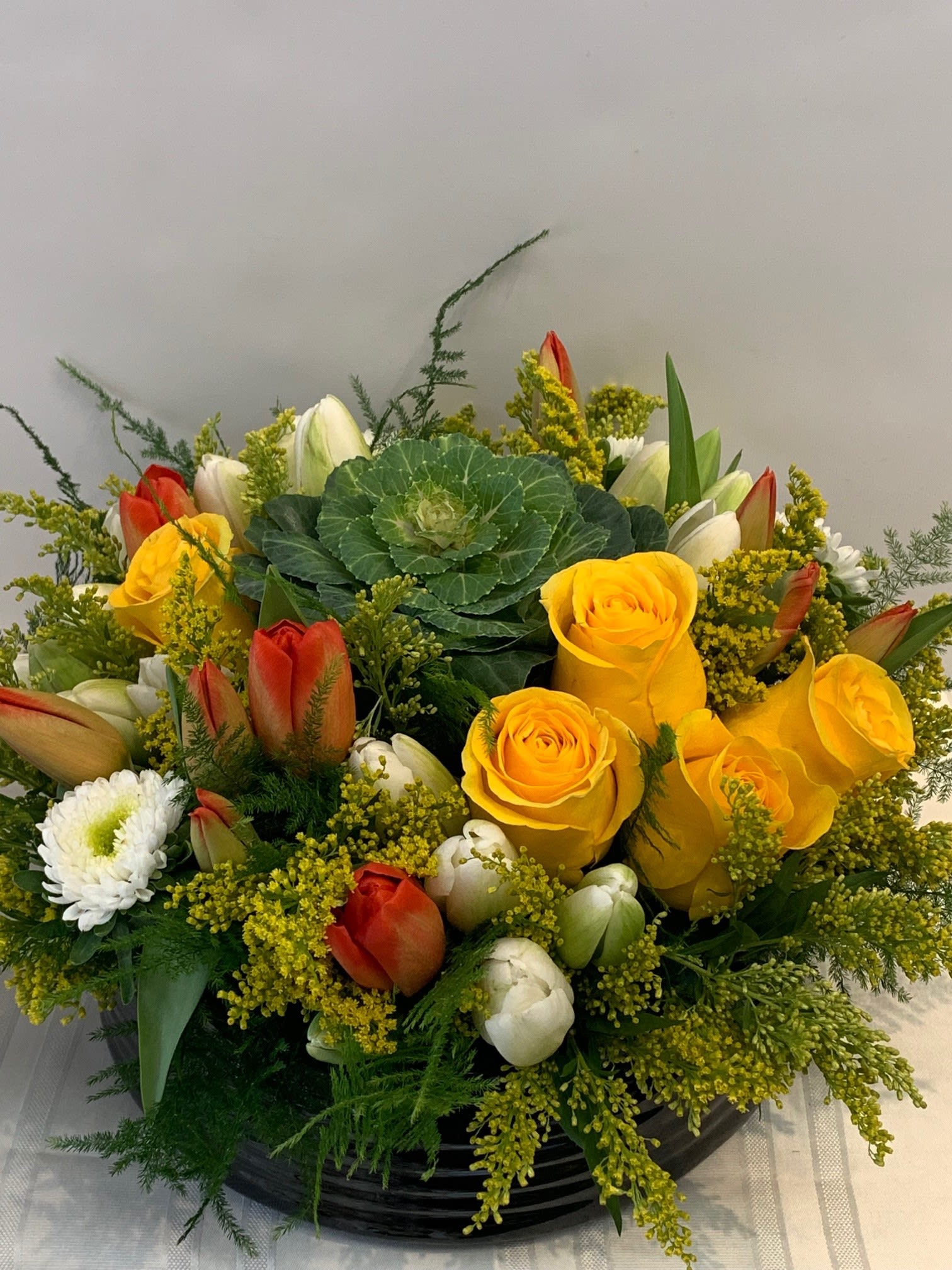 Hill of Flowers - with Roses, Kayle, Tulips, Asters, in ceramic round container - W698 - This beautiful yet subtle, large center piece is Fillmore Florists interpertation of a natural hillside covered with gorgeous flowers. Made with fresh Roses, Tulips, Asters, Cabbage flower, and solid asters, this stunning center piece is large and sure to impress your guests. W698 Dimensions Approximately: 8&quot; H x 15&quot; W