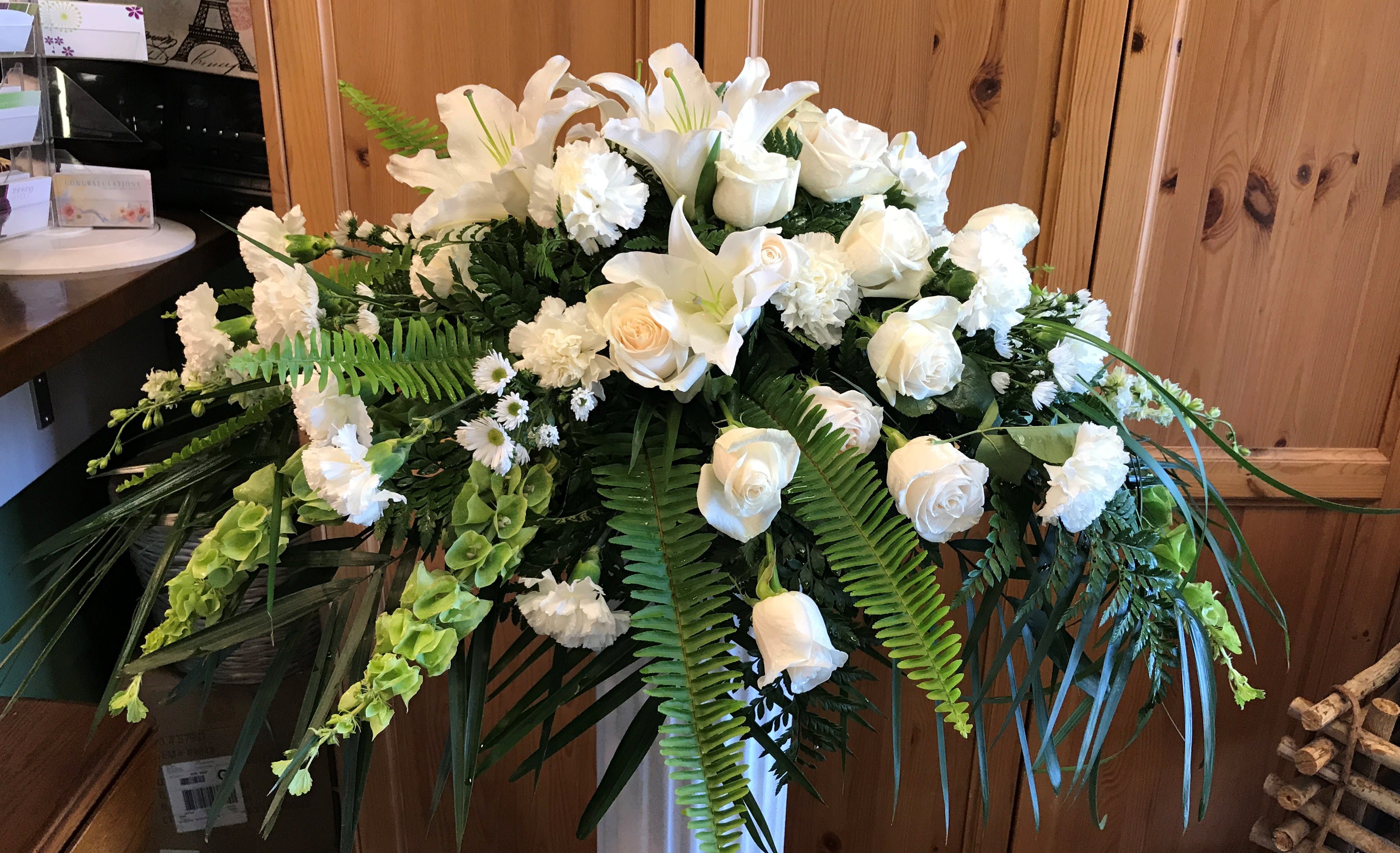 Eternal Peace - Casket Piece  White with green: Lilies, Roses, Carnations, Bells of Ireland, Larkspur 