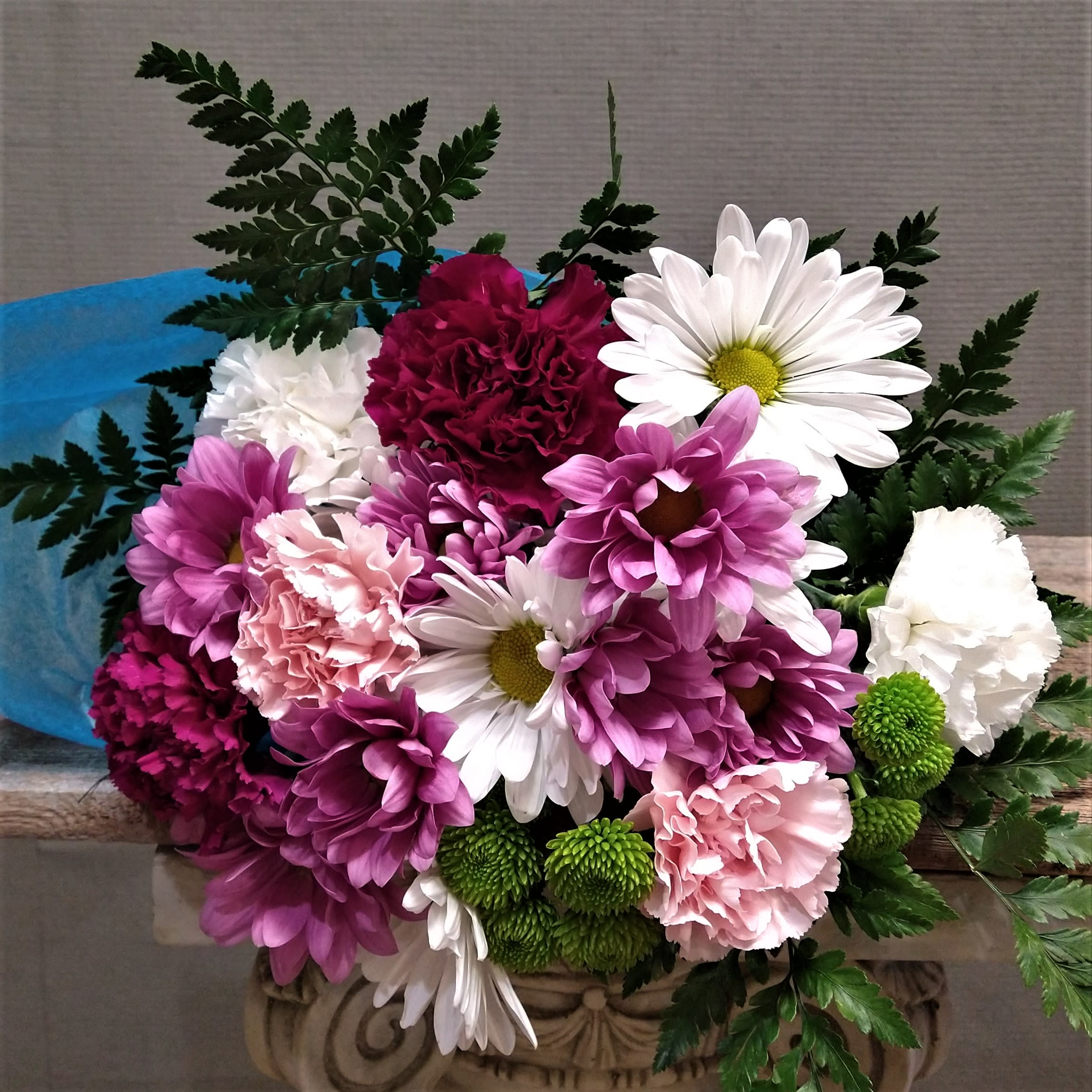 Cupid's Posey - A wrap of long lasting daisies and carns in pink, purple, and white. If you have a different color preference,  please specify in special instruction. For the recipients who already have a vase at home.