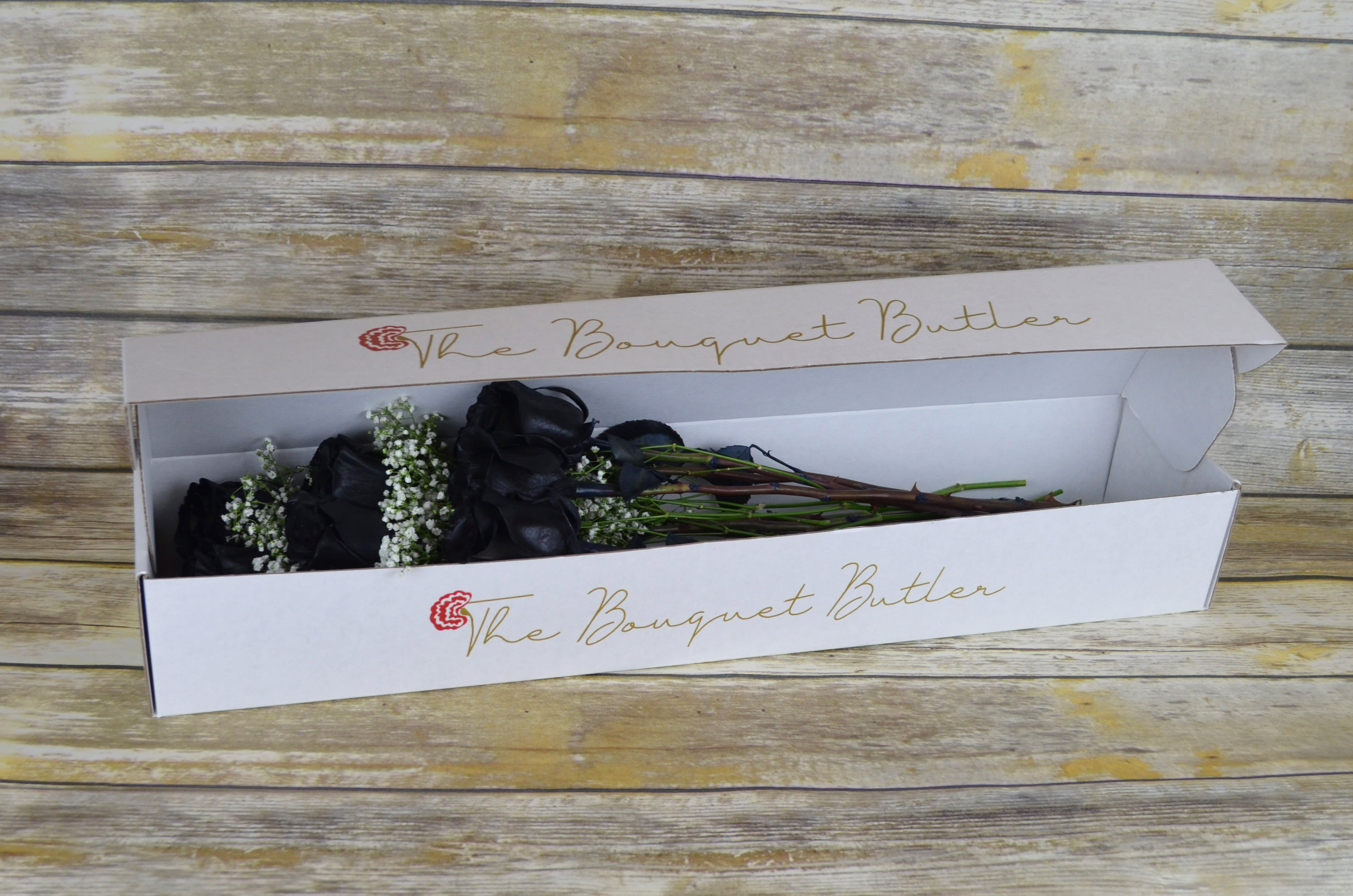 Black Velvet - Boxed - These breath taking roses are a perfect yet bold accent and tend to give a modern-chic vibe. All bouquets are arranged by our professional floral design team accented with seasonal filler (i.e. greenery, baby’s breath, etc.) inside a gift box. Blooms are hand delivered in person to enhance any celebration or a “just because” surprise. When artistically designed in a clear glass vase arrangement measures approximately 23&quot;H x 18&quot;L.  *These are specialty roses, therefore they will require a 7 day minimum order date.