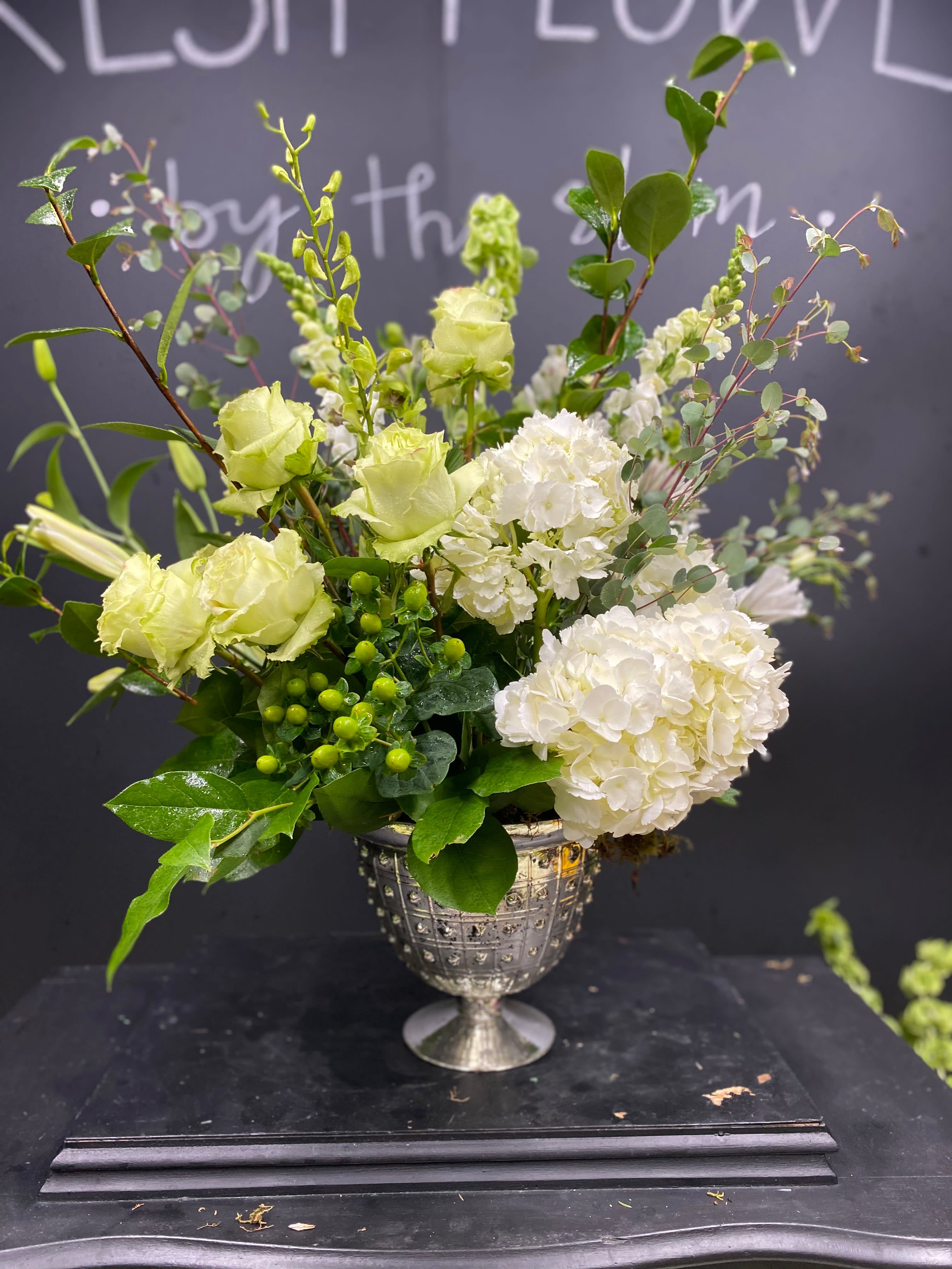 ELEGANT GREEN AND WHITE ELEGANT GREEN AND WHITE - Beautiful green and white arrangement in our elegant silver glass vase. Vases are hand selected by our designers and are made to reuse long after this arrangement is gone. Each arrangement purchased is similar to the one shown but is custom made for each order, so there may be slight variances. Version Pictured Includes: green roses, white hydrangeas, belles of ireland, green hypericum