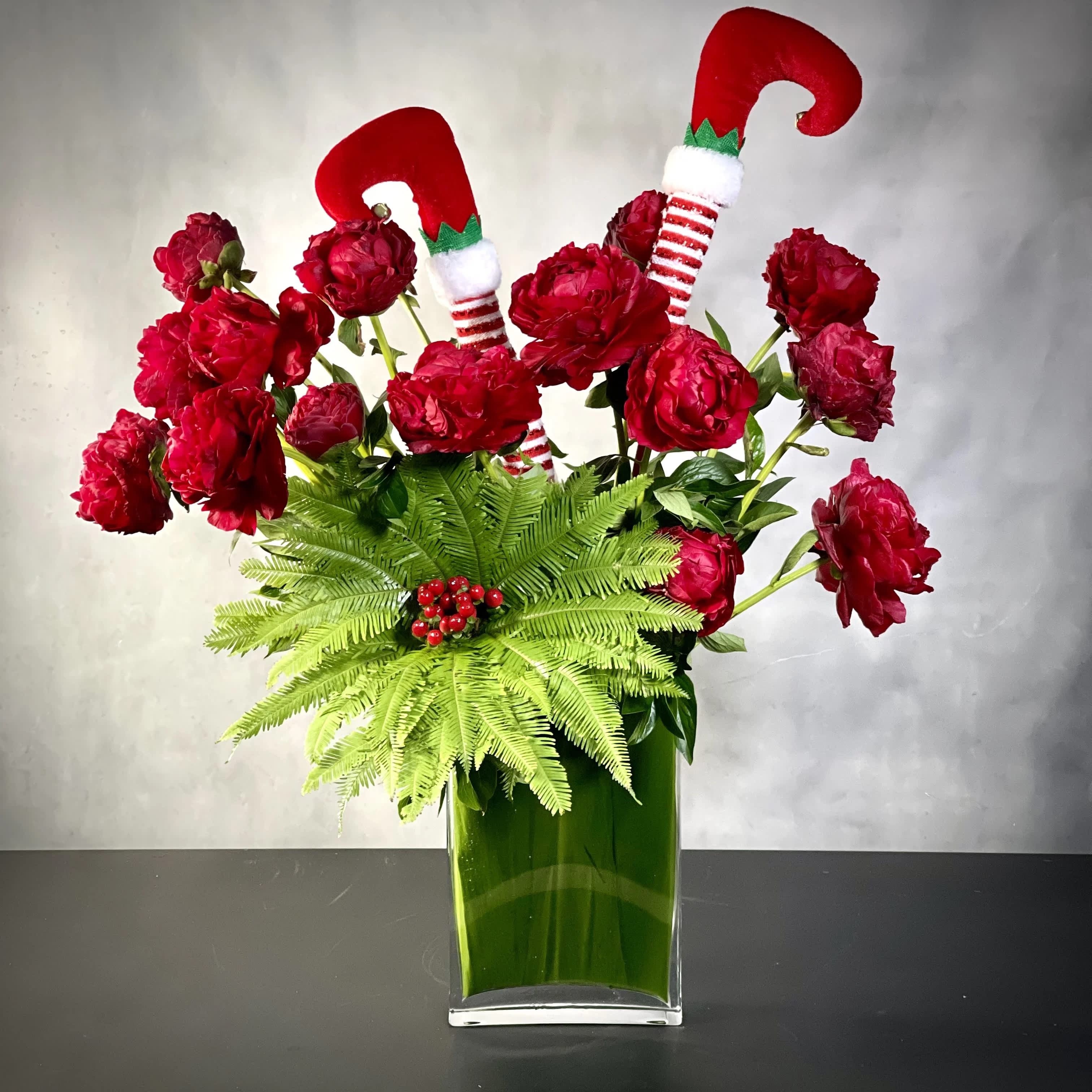Tipsy Turns - A few tipsy turns into the holiday spirit. This piece will bring holiday cheer with jollification to the center of your table. Making it a great centerpiece for your event. This arrangement includes a beautiful array of 16 deep red peonies, Umbrella Fern and red coffee beans. 