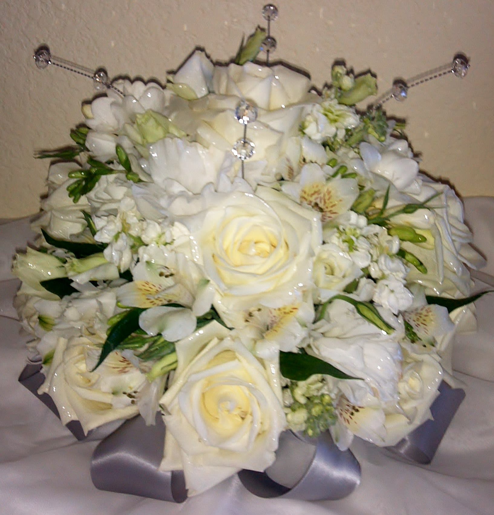 Romantic White Center Romantic White Center - All white round centerpiece composed of Roses, Lisianthus, Alstroemeria, Stock, & Freesia. Accented with crystals and satin ribbon. Design measures approx. 13"W x 10 1/4"H. Discounted rate available for orders of 6 or more. All event centers must be ordered a minimum of 72 hours in advance.