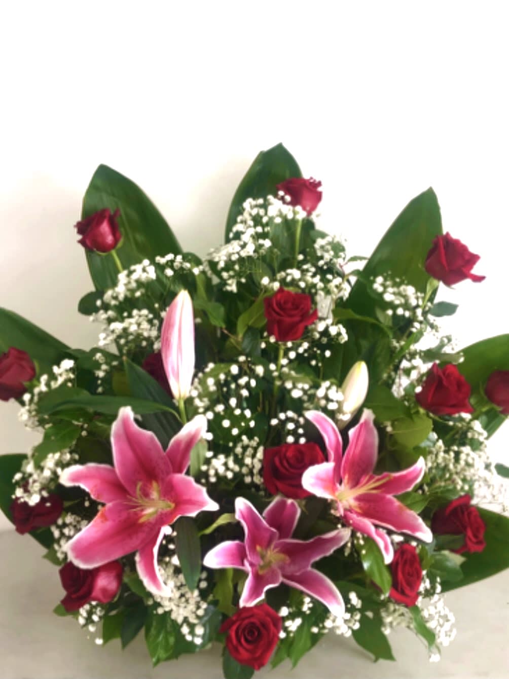 Paradise Palm Paradise Palm - Tangible paradise perfect for that special someone. Arrangement contains pink lilies, roses, baby’s-breath and some greens.