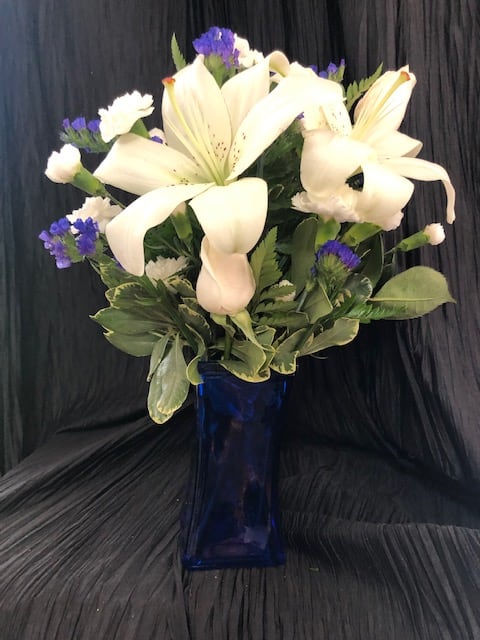Blue skies - Blue vase filled with white flowers and blue statice. Has roses, mini carnations and lily