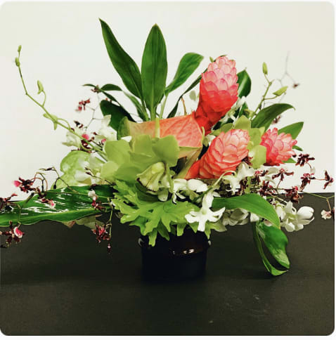 Vintage Hawaiian  - Evoking the feeling of beauty found in a backyard garden this lush arrangment is comprised of a mix of jeweled and soft tone blooms.  Designed in a rustic themed vessel.  Designed to be viewed from all angles.  Enhanced option includes additional blooms and foliage.  All floral arrangments are designed to a style and use seasonal materials of varying content.  Please contact us directly for any custom orders or requests info@helemelebotanicals.com or 808.226.7667  We are committed to malama 'aina and strive to use locally sourced material, reduce packaging and reuse and recycle where possible. We will pick up any of our product (vessels, plants and floral supply material) when delivering a subsequent order. At that time, a $5 credit toward future purchase will be issued for each ceramic, metal or wood vessel returned.