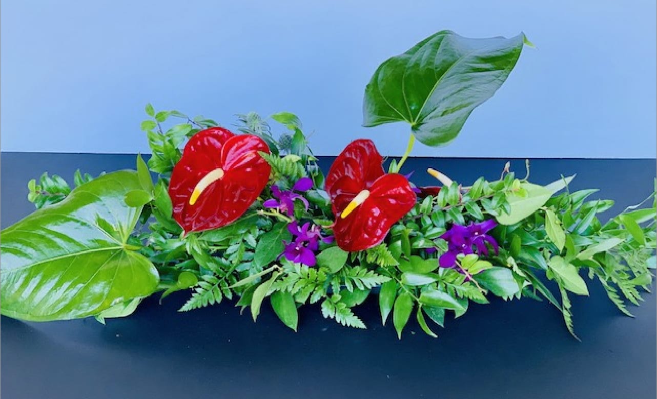 Garden-like arrangement - Garden-like arrangement that is designed with tropical and seasonal blooms with accents of blooms to create a visual delight.  The perfect display for a special occasion.  Designed to be placed on a flat surface and offered by the foot to accomodate a variety of surface lengths.    All garlands are made using seasonal material and will vary in content.  Please contact us directly for any custom orders or requests info@helemelebotanicals.com or 808.226.7667.  We are committed to malama 'aina and strive to use locally sourced material, reduce packaging and reuse and recycle where possible. We will pick up any of our product (vessels, plants and floral supply material) when delivering a subsequent order. At that time, a $5 credit toward future purchase will be issued for each ceramic, metal or wood vessel returned.