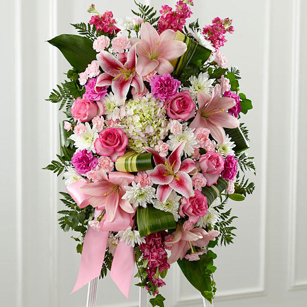 Gently into the Ever-After Standing Spray - Bright fresh beautiful and just right for an elegant expression of heartfelt sorrow and devastating loss. This classic standing arrangement is constructed by a local FTD artisan florist of hand-selected pink blossoms ranging from pale pastels to deep blushing pink. It includes roses carnations stock cushion pompons Asiatic and Stargazer lilies and hydrangea beautifully set among a field of lush contrasting greens like aspidistra and ivy vines. It comes with a wooden easel for flexible display options and makes an impressive memorable tribute at a wake funeral or graveside service.