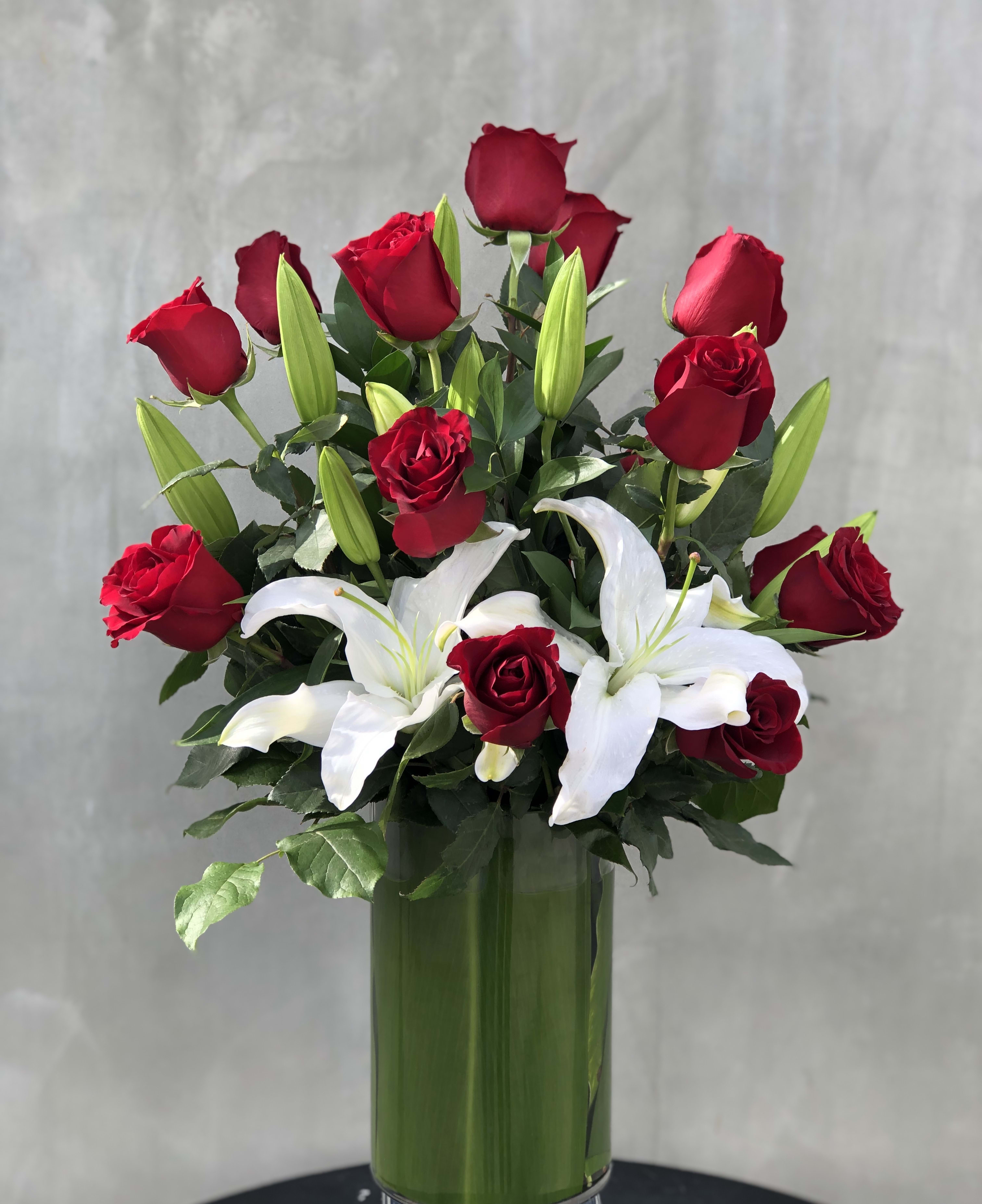 Romance Romance - Lovely red roses with Casa Blanca lilies arranged in a tall glass vase a beautiful arrangement for your love ones.