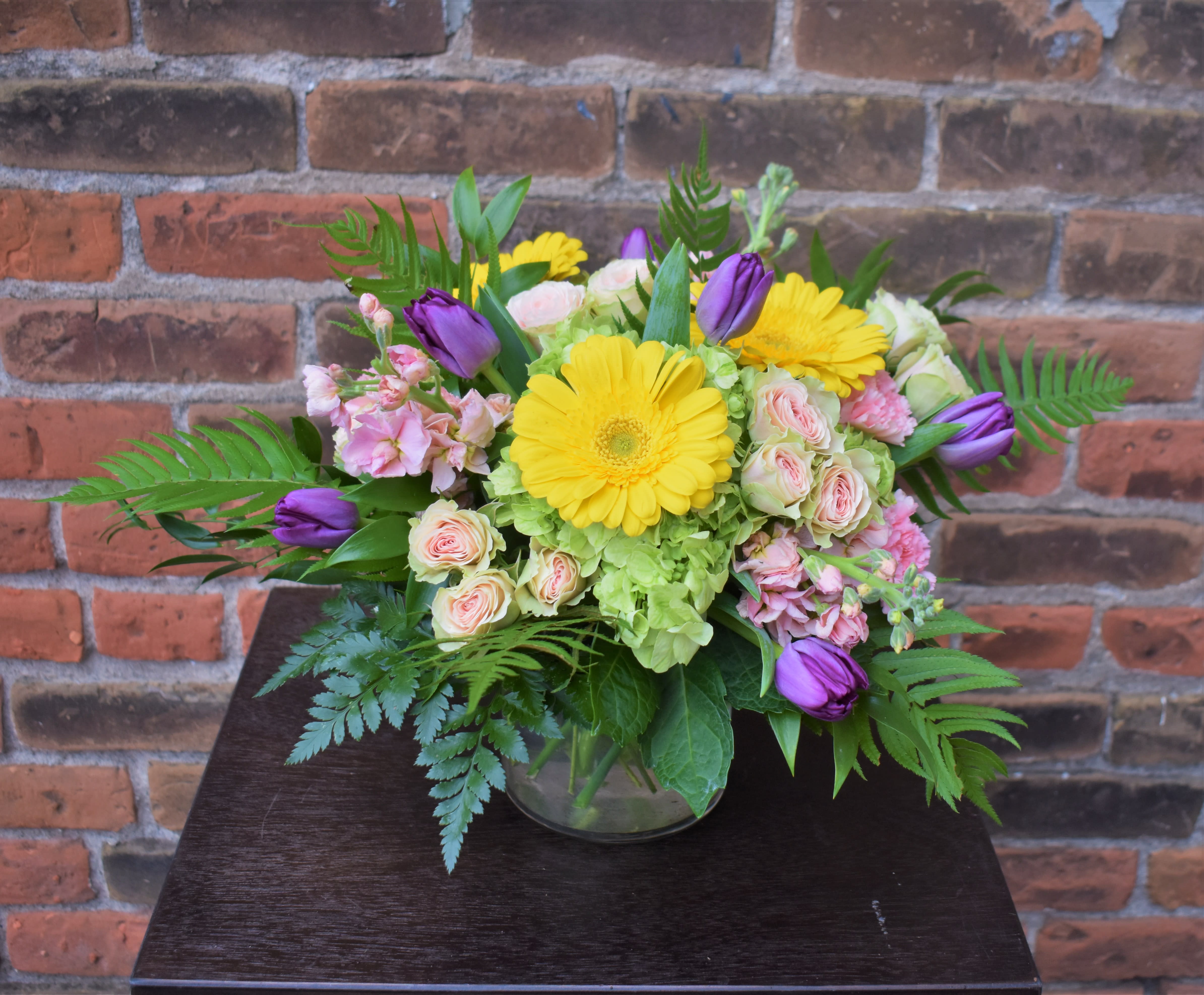 Pastel Elegance - Spring-time blooms of tulips, gerber daisies, hydrangea, spray roses, stock, and spring greens are arranged in a clear vase and make an elegant design bursting with hopeful colors...perfect for celebrating the season!  Design size is Approx. 12&quot;X12&quot;