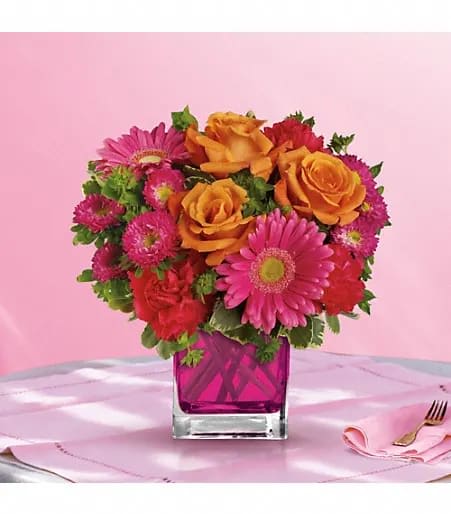 Turn Up the Pink - Turn up the heat with this hot pink, haute couture creation! Super chic and oh-so-fun in its fuchsia Cube vase, this girly mix of gerberas and roses is sure to warm her heart. This brilliant bouquet of lush orange roses, hot pink gerberas, carnations and matsumoto asters are accented with bupleurum and variegated pittosporum. Delivered in a glass Cube.