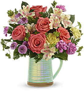 Pour on the Beauty Pour on the Beauty - Beautiful all the way around. This irridescent aqua pitcher filled with orange roses, yellow alstro, lavender mums, and a splash of bright yellow.
