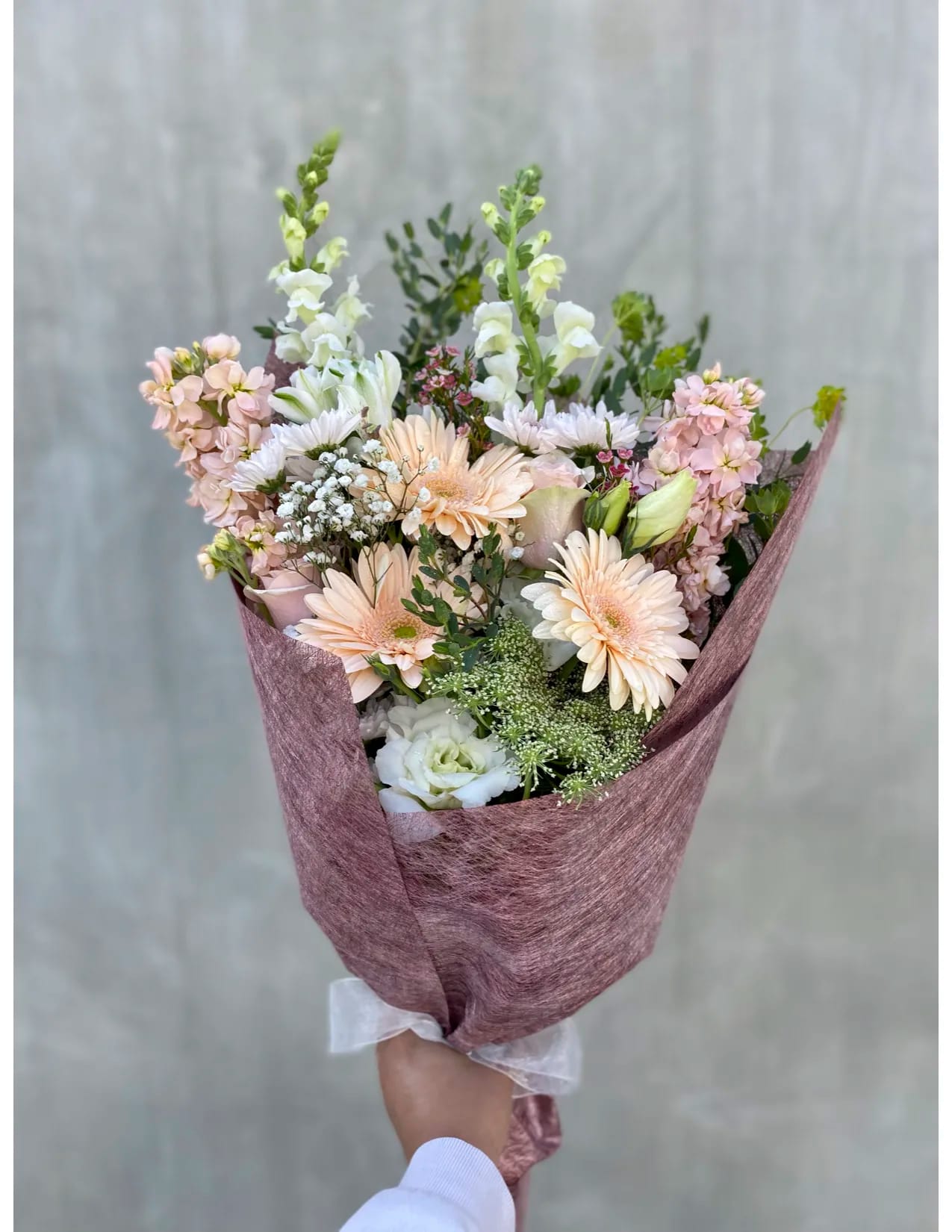 Soft Palette Bouquet Soft Palette Bouquet - This beautifully hand-tied bouquet includes gerberas, snapdragons, lisianthus, baby's breath, stalks, roses, and more.