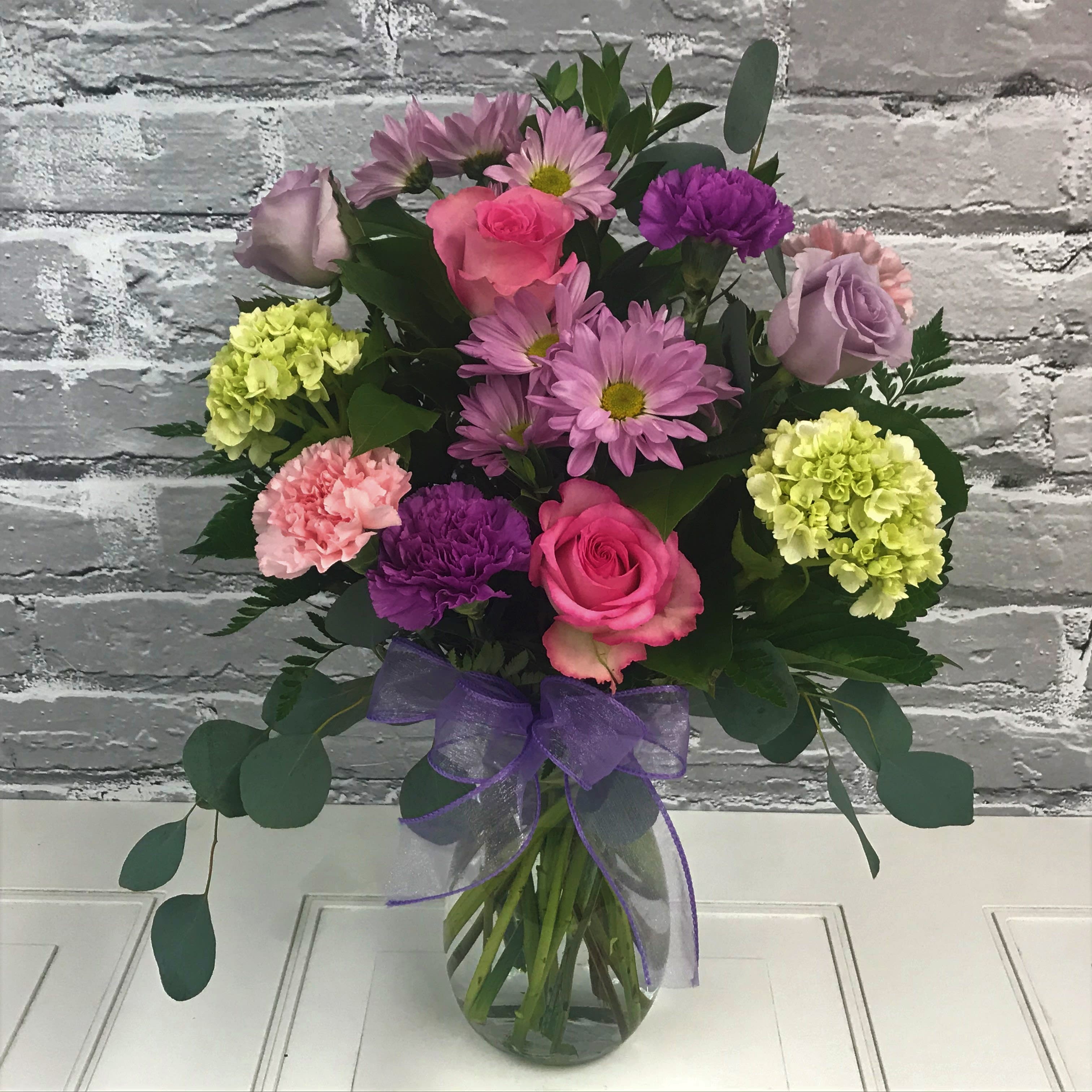 Moonlight - Lovely shades of lavender and pinks designed beautifully in a glass vase. Roses, Carnations, Daisies, Green Hydrangeas included. 