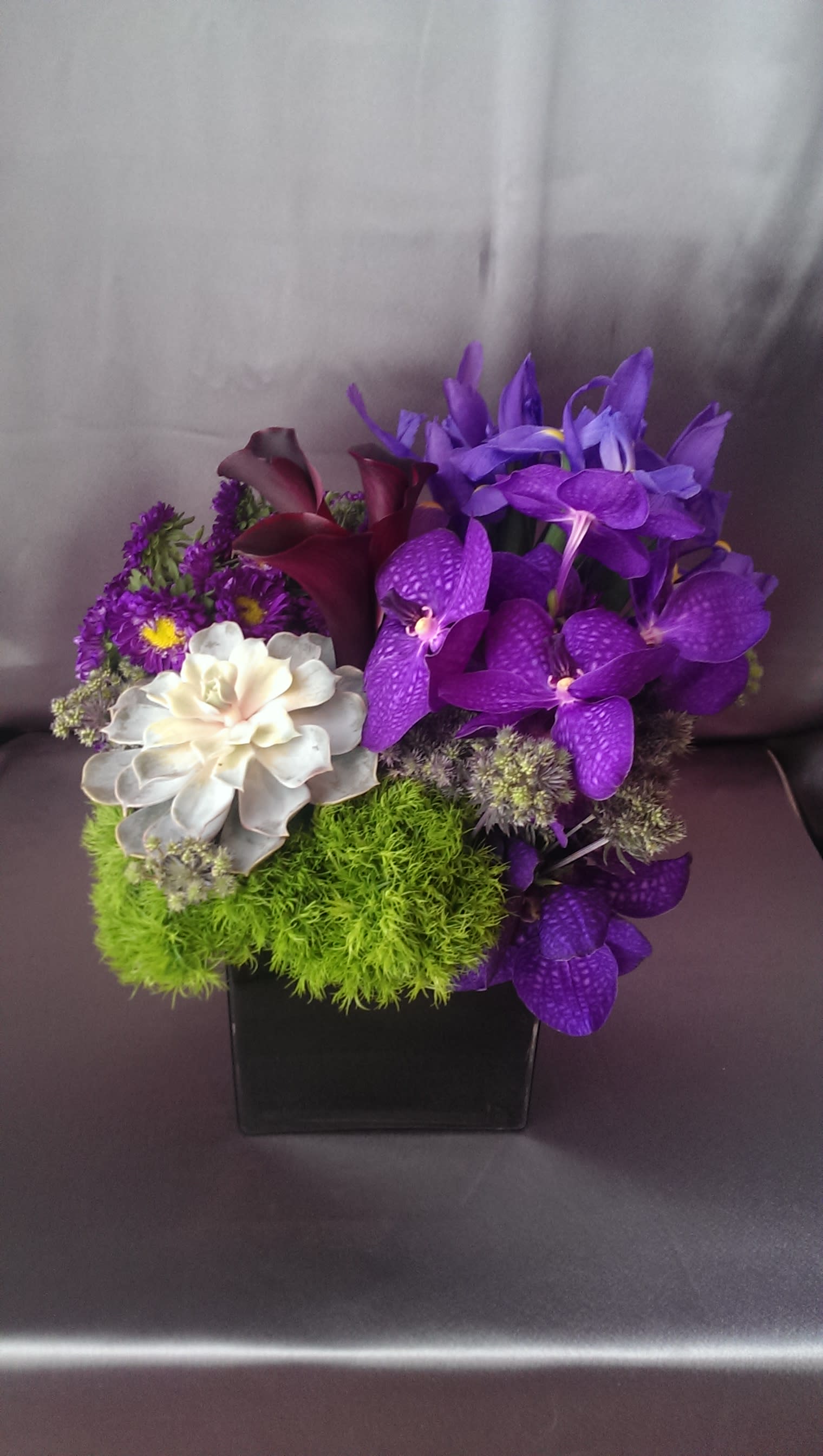 Purple Haze - Vanda orchids, Iris, thistle, trick, matsamoto, calla lilies, &amp; succulent in a black square   container.