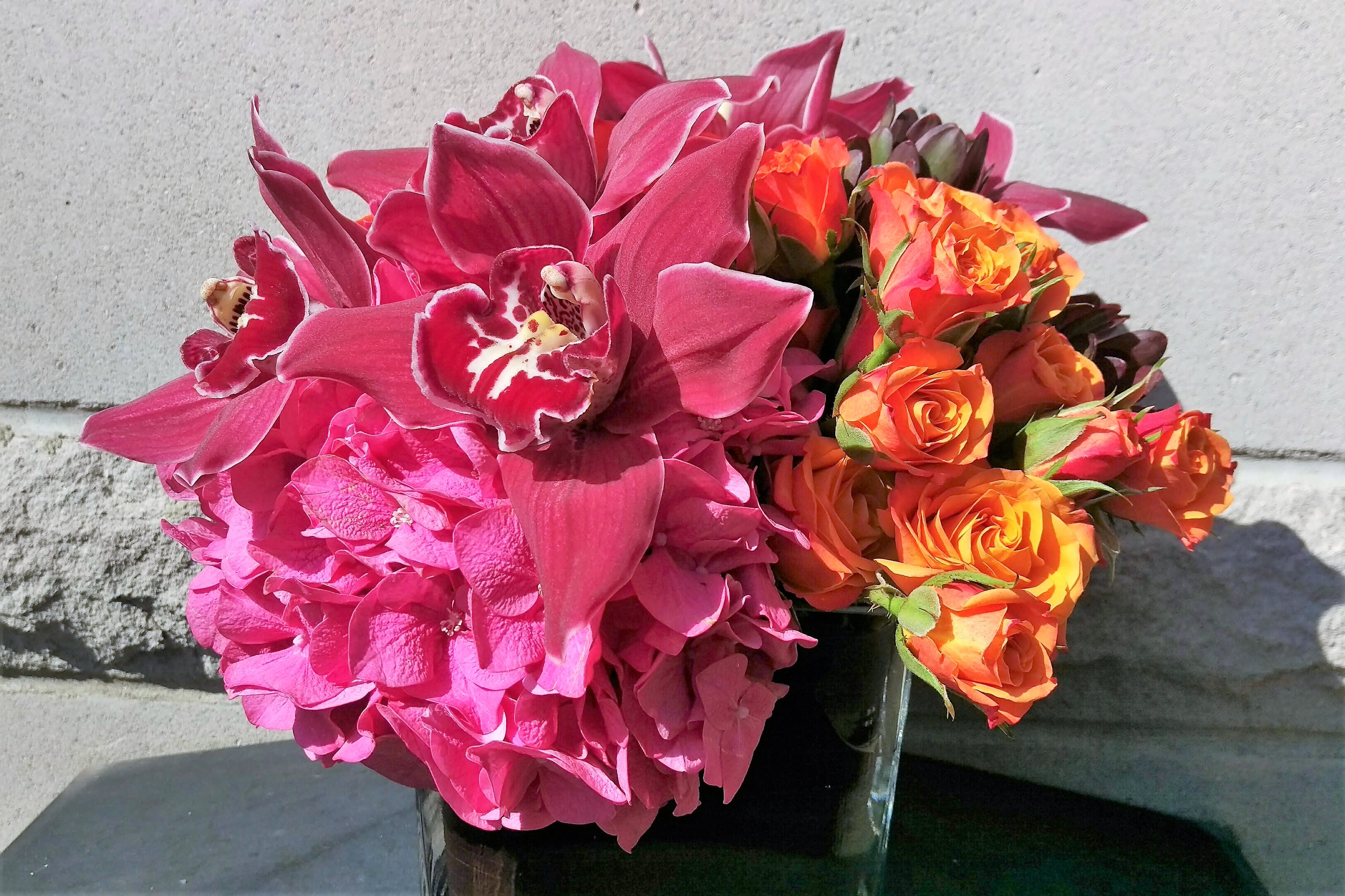 Samantha - Hydrangea, cymbidium orchids &amp; spray roses in a ti leaf wrapped glass square container