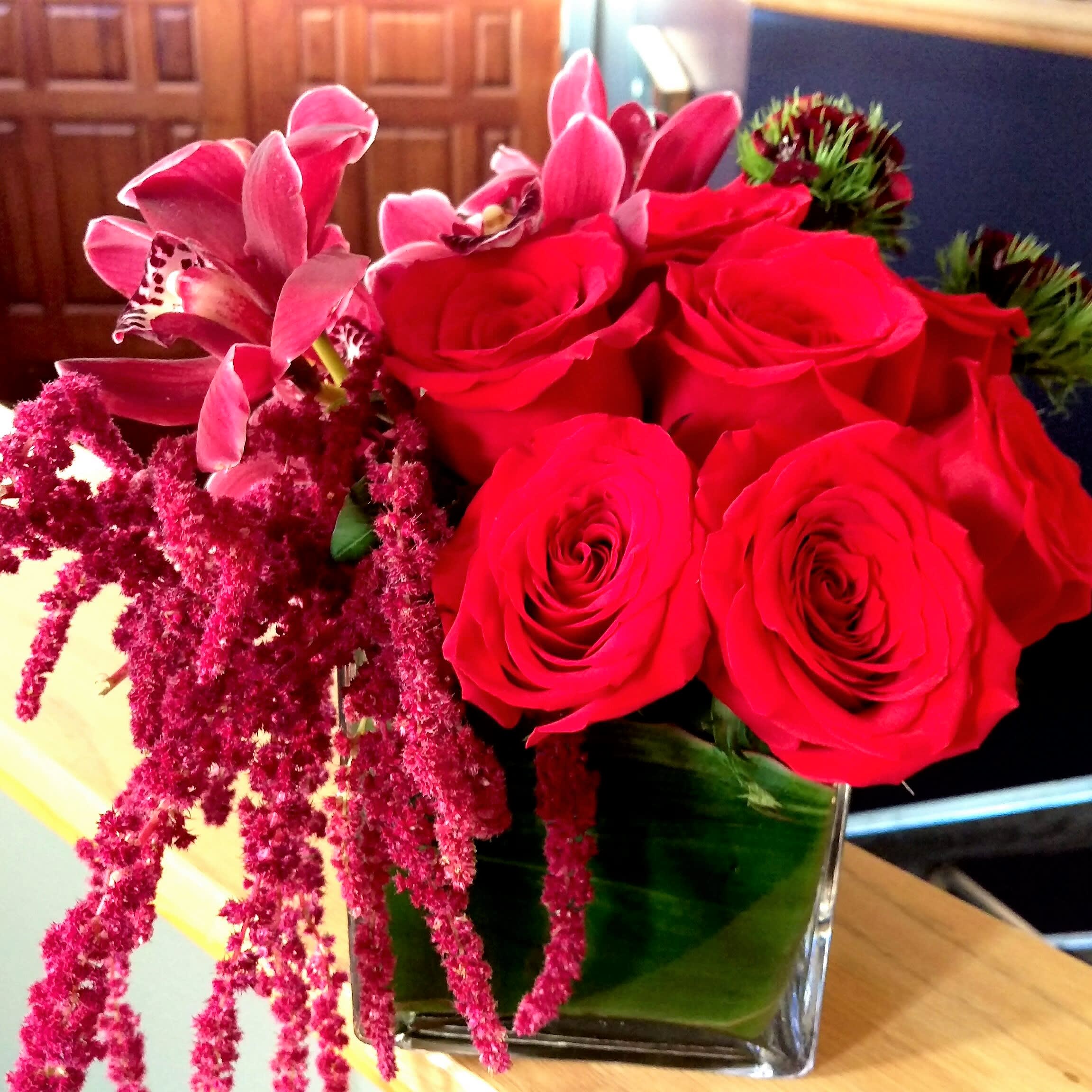 Red Hott - Roses, cymbidium orchids &amp; hanging amaranthus in a ti leaf wrapped square container