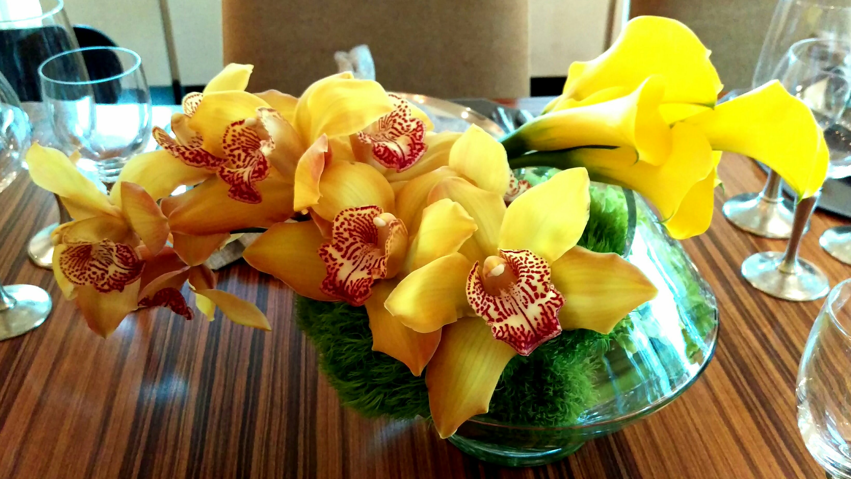 Goldie - Cymbidium orchids, calla lillies, &amp; trick in a round glass container